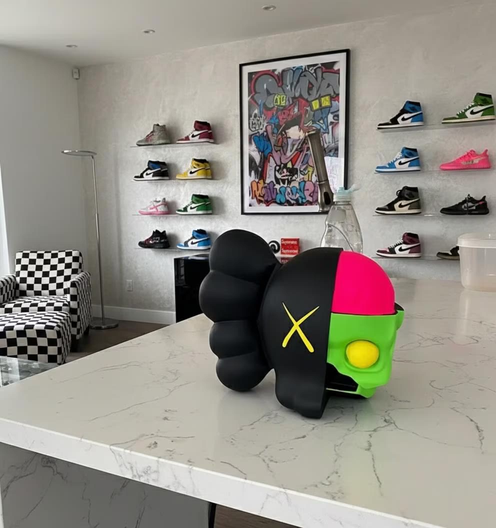 Alien Table Ornament — a black and white figure on a marble counter, in a room with shelved trainers.