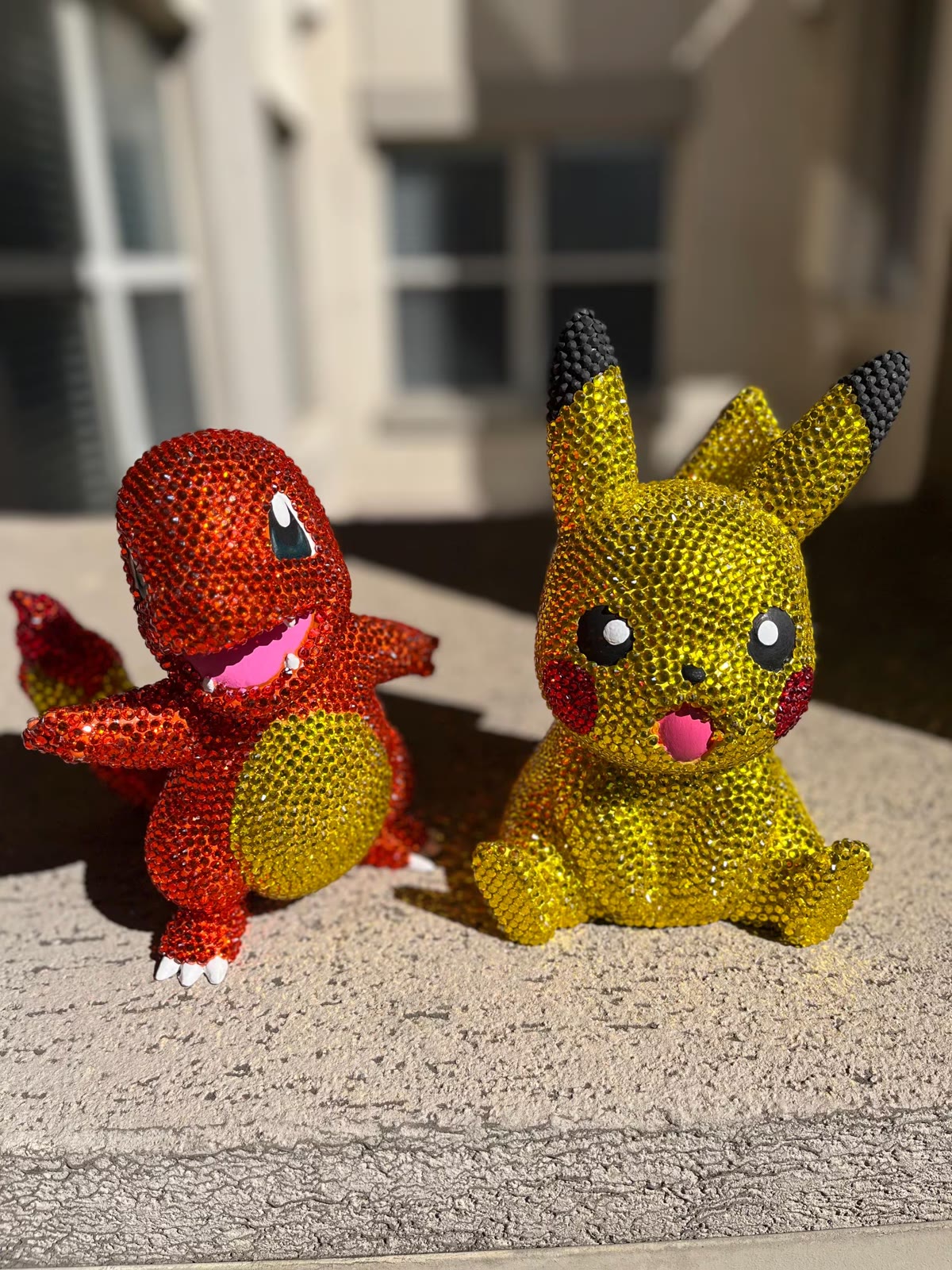 Bedazzled figurines — two rhinestoned figures, one red and one yellow, outdoors.