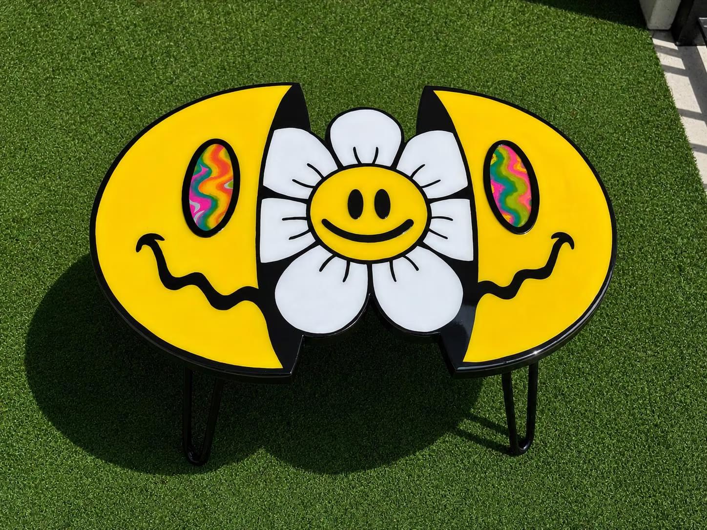 Split Reality — a yellow smiley flower tabletop, split into two halves, on grass.
